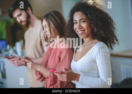 Dunkelhaarige Mädchen drehte ihr Gesicht zur Kamera, Freunde in der Nähe Stockfoto