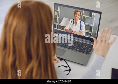 Online-Arzt. Ältere Frau Arzt mit grauen Haaren hört Patienten Video-Chat-Computer zu Hause. Stockfoto