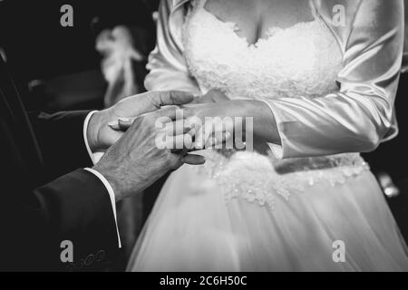 Bräutigam legte den Ehering an Braut Finger in der Kirche während der Trauung. Schwarzweiß-Foto. Matteffekt Stockfoto