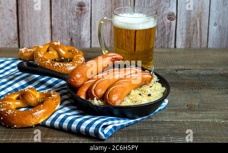 Traditionelle deutsche Bratwurst mit Sauerkraut, Bier und Brezeln Stockfoto