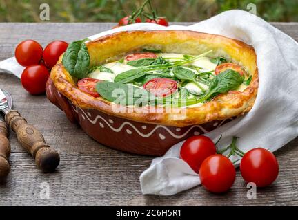 Nahaufnahme von vegetarischen Spinatkuchen oder Quiche mit Feta und Mozzarella mit Tomaten. Stockfoto