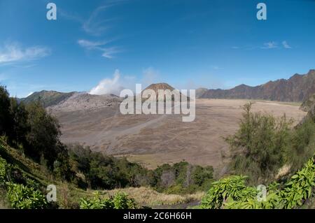 Blick über das Meer aus Sand des rauchenden Mount Bromo auf der linken Seite und Mount Batok auf der rechten Seite, Bromo Tengger Semeru Nationalpark, Ost-Java, Indonesien Stockfoto