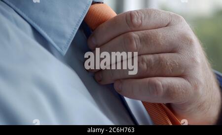 Elegantes Geschäftsmann-Image trägt blaues Hemd und macht einen Knoten zu einer Orange Krawatte. Stockfoto