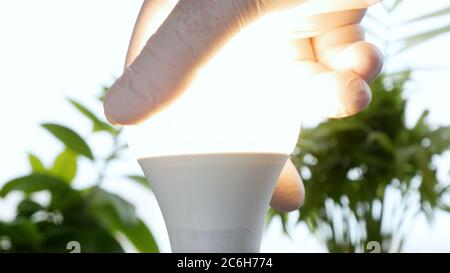 Die Hand eines Elektrikers dreht eine LED-Glühlampe in der Steckdose, um das Licht zu aktivieren Stockfoto
