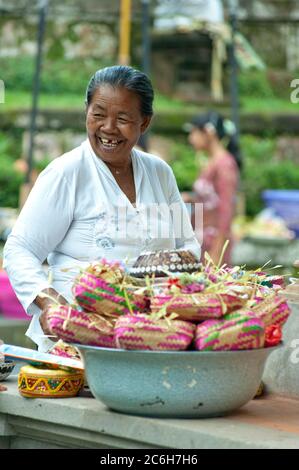 Lächelnde Frau bei Opfergaben während des Siat Sampian Coconut Leaf war Festivals, Pura Samuan Tiga, Ubud, Bali, Indonesien Stockfoto