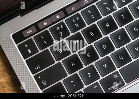 Nahaufnahme, geringer Fokus einer hintergrundbeleuchteten Tastatur, die auf einem bekannten, luxuriösen Computerhersteller zu sehen ist. Stockfoto