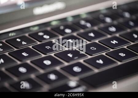 Nahaufnahme, geringer Fokus einer hintergrundbeleuchteten Tastatur, die auf einem bekannten, luxuriösen Computerhersteller zu sehen ist. Stockfoto