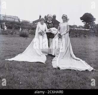 1950er Jahre, historische, lokale Teenager-Mädchen, die Rose Queen und ihr Präzedenzfall, stehen in einem Parkfeld in ihren Gewändern in Farnworth, Bolton, Lancashire, England, Großbritannien. Das jährliche Rose Queen Festival, das im Juni in den 1880er Jahren stattfand, wurde nach den Kriegen der Rosen von 1455-87 zu einem wichtigen jährlichen Ereignis in vielen Städten und Dörfern in ganz Großbritannien, insbesondere in Lancashire, dem sogenannten Red Rose County. Stockfoto