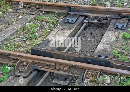 Zrenjanin, Serbien, 04. Juli 2020. Die Eisenbahn ist vernachlässigt, verwüstert, veraltet und mit Gras bewachsen. Manuelle Schaltanlage, die zwei Gleisschienen verbindet Stockfoto