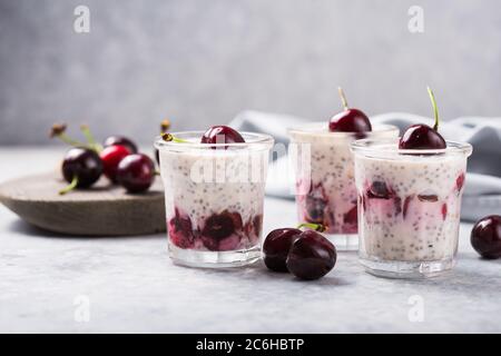 Chia Pudding mit Kirschbeeren, Naturjoghurt, in einem Glas auf einer grauen Oberfläche. Selektiver Fokus. Gesunde Nachtisch, richtige Ernährung, super Essen. Stockfoto