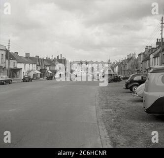 1950, historisch, die breite Hauptstraße von Chipping Sodbury, eine Marktstadt in South Gloucestershire, England, wie in dieser Zeit gesehen. Keine gelben (Parkplatz-)Linien, keine Unordnung auf der Straße, Grasrand. Interessant ist auch die Skyline der Stadt, ohne hohe Gebäude. Stockfoto