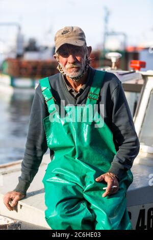 KAPSTADT, SÜDAFRIKA – 4. JULI: Nicht identifizierter alter Fischer auf dem Boot, nachdem er den Fang des Tages im Hafen von Kalk Bay gebracht hat Stockfoto