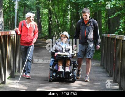 10. Juli 2020, Sachsen, Leipzig: Im Auenwald beginnen die Kartographin Katharina Kohnen und Andre Neutag (r), Physiotherapeutin und Heilpädagogin mit Schwerpunkt Inklusion, eine viertägige Wanderung von Leipzig nach Dresden. Benny Tröllmich (l.), Berater des Vereins Leben mit Handicap, der selbst blind ist, begleitet sie auf den ersten zwölf Kilometern. Die 28-jährige Katharina, die aufgrund einer Muskelerkrankung auf einen elektrischen Rollstuhl angewiesen ist, und der 31-jährige Andre wollen auf ihrer Wanderung auf Einschlussprobleme im Alltag hinweisen. Beide wurden invo Stockfoto