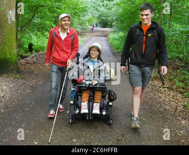 10. Juli 2020, Sachsen, Leipzig: Im Auenwald beginnen die Kartographin Katharina Kohnen und Andre Neutag (r), Physiotherapeutin und Heilpädagogin mit Schwerpunkt Inklusion, eine viertägige Wanderung von Leipzig nach Dresden. Benny Tröllmich (l.), Berater des Vereins Leben mit Handicap, der selbst blind ist, begleitet sie auf den ersten zwölf Kilometern. Die 28-jährige Katharina, die aufgrund einer Muskelerkrankung auf einen elektrischen Rollstuhl angewiesen ist, und der 31-jährige Andre wollen auf ihrer Wanderung auf Einschlussprobleme im Alltag hinweisen. Beide wurden invo Stockfoto