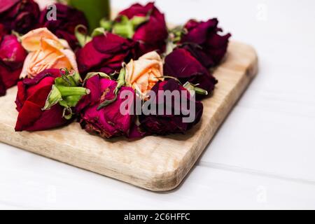 Getrocknete violette Rosenknospen auf Holztafel. Getrocknete Rosenblätter auf Weiß Stockfoto