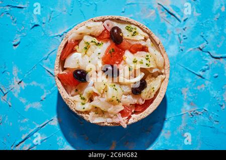 Blick in den hohen Winkel von einem Teller mit esqueixada de bacalla, ein kaltes Gericht mit Kabeljau, Tomaten, Zwiebeln und schwarzen Oliven, und mit Olivenöl, Typi gekleidet Stockfoto