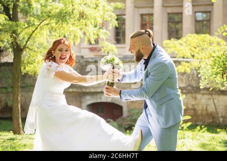 Gerade verheiratet liebevolle Hipster-Paar in Hochzeitskleid und Anzug im Park. Glückliche Braut und Bräutigam laufen und tanzen. Romantisch verheiratet junge fa Stockfoto