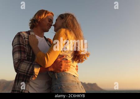 Kaukasisches Paar umarmt auf einer Promenade während des Sonnenuntergangs Stockfoto