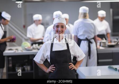 Portrait einer Köchin mit Schürze, die lächelt in der Restaurantküche Stockfoto