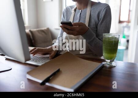 Mittlere Abteilung der Frau im Vorfeld mit Computer und Smartphone Stockfoto