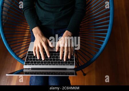 Mittlere Abteilung der Frau mit Laptop auf einem Stuhl sitzen Stockfoto