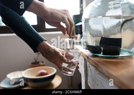 Mittlere Abteilung der Frau, die zu Hause Wasser in ein Glas gießt Stockfoto