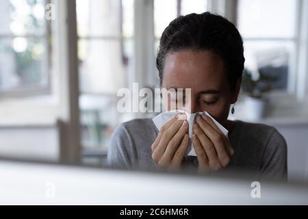 Frau, die zu Hause ihre Nase bläst Stockfoto