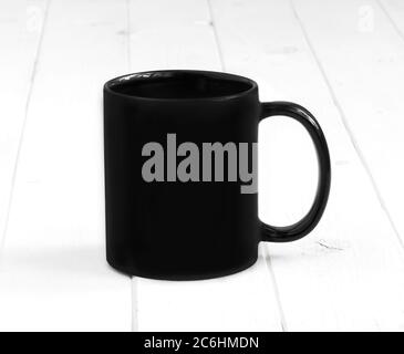 Schwarze Tasse auf einem weißen Planken-Tisch Stockfoto