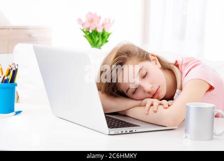 Netter Teenager schlief am Schreibtisch ein, wenn er am Laptop arbeitete Stockfoto