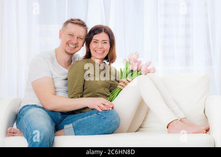 Glücklich schönes Paar auf der Couch mit Überraschung Bouquet sitzen Stockfoto