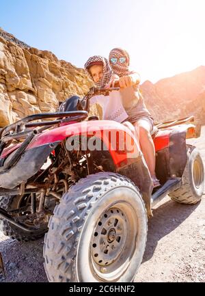 Ein Paar, Kind mit Trainer sind auf roten Quad-Bike in der Wüste Safari fahren Stockfoto