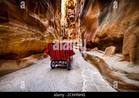 Pferdewagen für Touristen, die durch den felsigen Eingang von Petra, Jordanien reiten Stockfoto