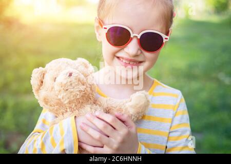 Portrait von niedlichen lächelnd kleinen Mädchen mit ihrem Lieblings Teddybär Spielzeug im Park Stockfoto