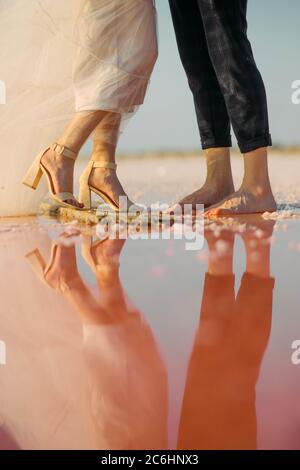 Spiegelung von Jungvermählten im Wasser des rosa salzigen Genitschesk-Sees in der Ukraine. Stockfoto