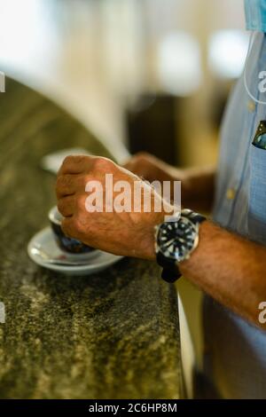 Bar-Kunde hält Tasse Espresso Kaffee Cappuccino Nahaufnahme über Kopf geschossen, Tageslicht, an der Bar, auf einem Tisch, selektive Fokus und Bokeh, flach Stockfoto