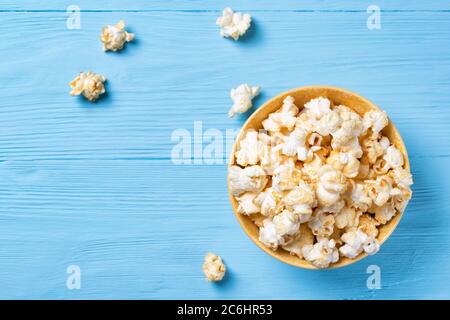 Süßes Popcorn in einer gelben Schüssel auf blauem Holzhintergrund, Draufsicht Stockfoto