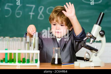 Kind studiert Biologie und Chemie in der Schule. Schulbildung. Erforschen Sie biologische Moleküle. Kleinkind Genie Baby. Junge in der Nähe von Mikroskop und Reagenzgläser in der Schule Klassenzimmer. Technologie und Wissenschaft Konzept. Stockfoto