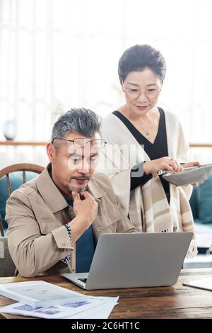 Paare mittleren Alters, die zu Hause einen Laptop benutzen Stockfoto