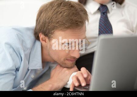Mann, der seine Frau am Computer arbeitet. Nahaufnahme Porträt des Mannes trägt runde dünne Gläser auf seinem Freund auf dem Bett und beobachtete ihre Arbeit an Stockfoto