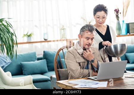 Paare mittleren Alters, die zu Hause einen Laptop benutzen Stockfoto
