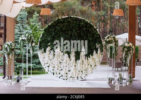 Runde aus Blumen und Blättern europäischen Stil Hochzeit Fotozone mit Blumen und Gläser mit Kerzen verziert Stockfoto