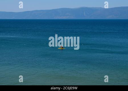 Ein Paddelboot auf dem Wasser bei Shaman Rock auf Olchon Island, Baikalsee, Russland Stockfoto