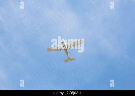 Kleines weißes schmutziges Single Engine Vintage Flugzeug in einem blau bewölkten Himmel Stockfoto