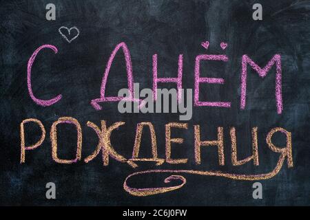 С днем рождения. Worte Happy Birthday auf Tafel in russischer Sprache geschrieben. Stockfoto