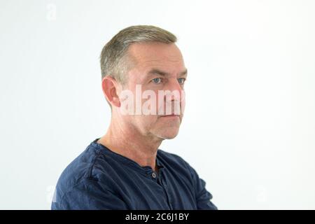 Dreiviertel-Pose eines ernsthaft nachdenklichen Mannes mittleren Alters, der in einem Kopf-Schultern-Portrait auf weißem Hintergrund zur Seite schaut Stockfoto