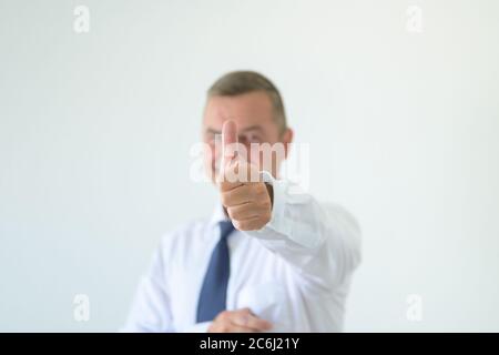 Erfolgreicher Geschäftsmann macht einen Daumen nach oben Geste mit Fokus auf die Hand in einem Kopf-und Schulterportrait auf weiß Stockfoto