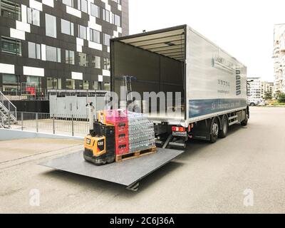 Getränke werden von einem Gabelstapler auf einem Heckklappenlader auf der Rückseite eines Lieferwagens vor einem Bürogebäude entladen. Kopenhagen, Dänemark - Ju Stockfoto