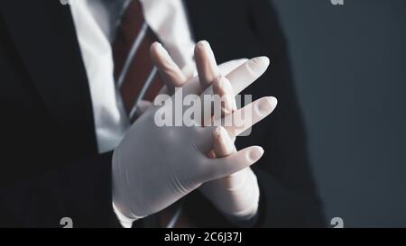 Hygienekonzept. Geschäftsfrau drückte die Daumen und korrigierte ihre Handschuhe im Vordergrund. Weibliche Hände in Latex-Schutzhandschuhen. Nahaufnahme. Getönt Stockfoto