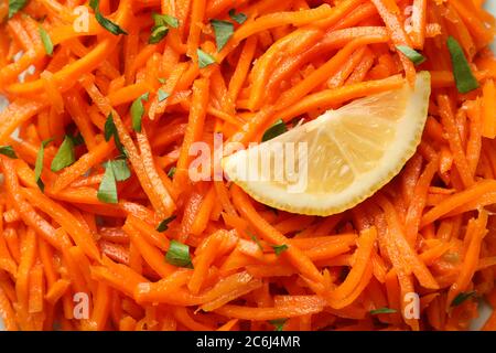 Leckerer Karottensalat mit Zitrone auf dem ganzen Hintergrund, Nahaufnahme Stockfoto