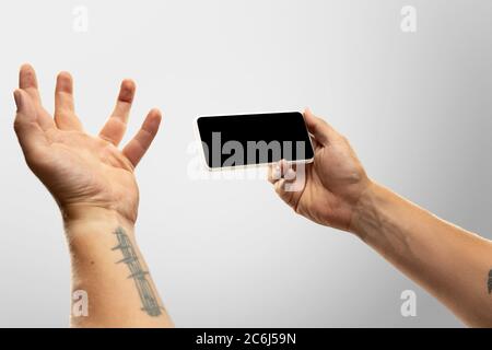 Spannende Momente. Nahaufnahme männliche Hände halten Telefon mit leerem Bildschirm während Online-Wiedergabe von beliebten Sportspielen, Meisterschaften. Copyspace für Werbung. Geräte, Gadgets, Technologien Konzept. Stockfoto